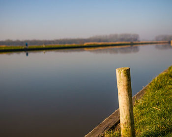 Wooden post in lake against sky