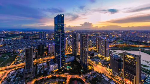 High angle view of illuminated city buildings against sky during sunset