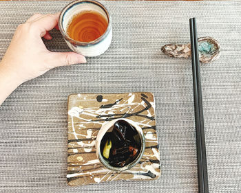 Directly above shot of hand holding coffee on table
