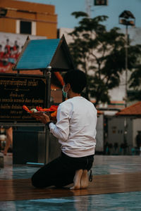 Rear view of man holding umbrella standing in city