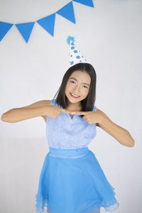 Portrait of a smiling young woman standing against wall