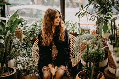 Young woman standing by potted plants