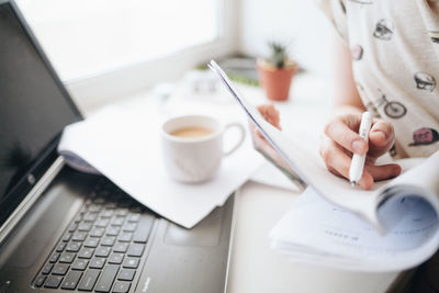 Midsection of woman writing on paper at home