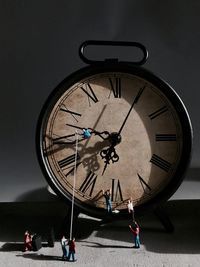 Close-up of figurines with alarm clock on table