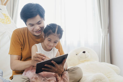 Little girl and young father are enjoying using tablet together.