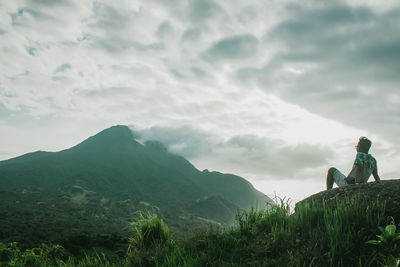 People sitting on mountain against sky