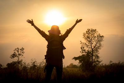 Rear view of silhouette person standing on field against sky during sunset