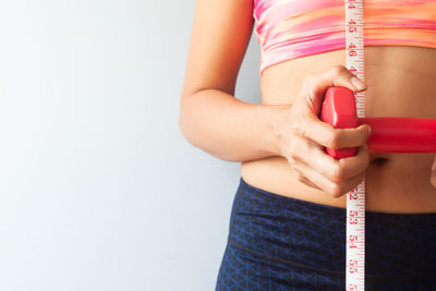 Midsection of woman holding hands against white background