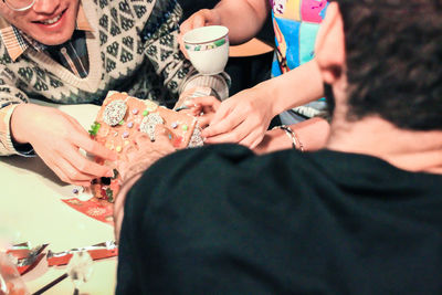 Midsection of couple holding hands while sitting on table