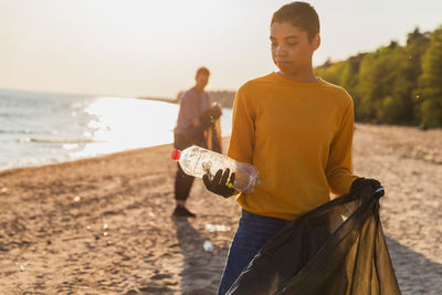 Side view of young man with surfboard at beach