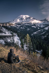 Low angle view of hiker sitting on mountain against sky