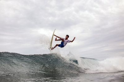 Man surfing in sea against sky