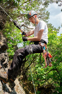 Full length of boy climbing on rock in forest