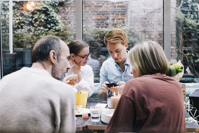 Siblings sharing smart phones during birthday party at restaurant