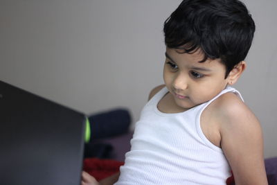 Close-up of little boy using laptop at home