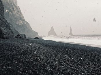 Scenic view of beach against sky during snowfall