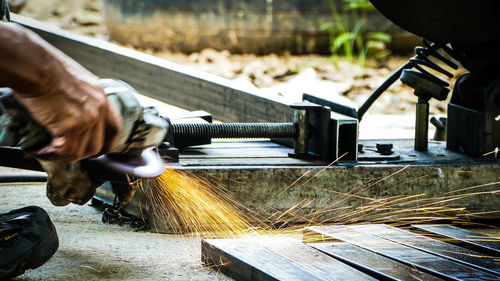 Cropped hand of worker grinding metal 