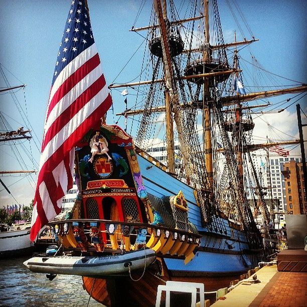 architecture, built structure, building exterior, flag, transportation, american flag, patriotism, nautical vessel, water, clear sky, famous place, travel destinations, sky, city, travel, national flag, international landmark, identity, tourism, mode of transport