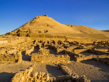 Scenic view of arid landscape against clear blue sky