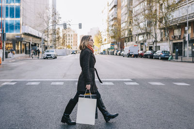 Woman with shopping bags crossing road in city