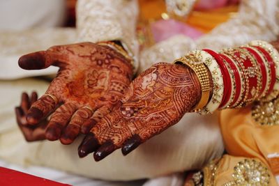 Midsection of couple showing henna tattoo on hands during wedding ceremony