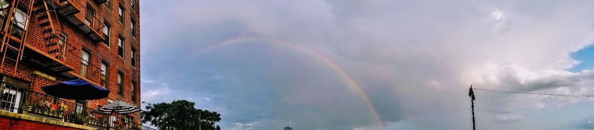 Low angle view of rainbow over buildings against sky