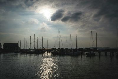 Boats in sea against cloudy sky at sunset