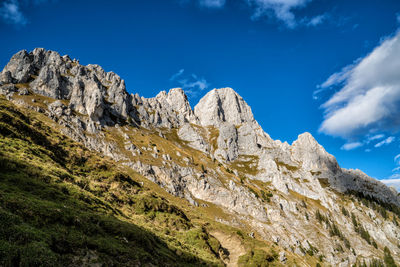 Low angle view of rocky mountains against blue sky