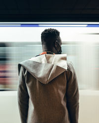 Rear view of man standing by train at subway station