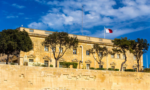 Built structure amidst trees and buildings against blue sky