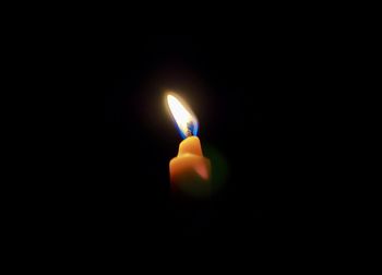 Close-up of lit candle in darkroom