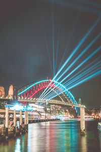 Illuminated bridge over river at night