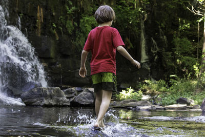 Boy wading in stream at forest