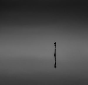 Silhouette tower by sea against sky