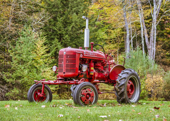 Tractor on field against trees in forest