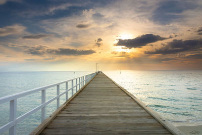 Pier over sea against sky during sunset