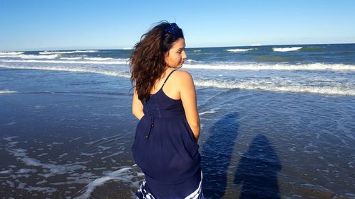 Woman standing on beach against sea