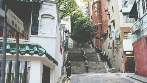 Rear view of man walking on street amidst buildings