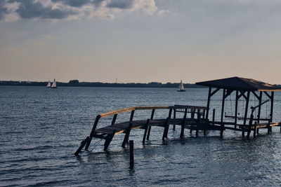 Pier over sea against sky during sunset