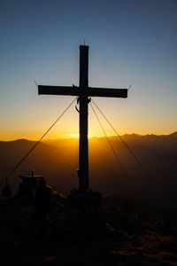 Silhouette cross against sky during sunset