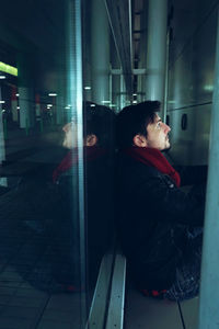 Side view of young man looking through window