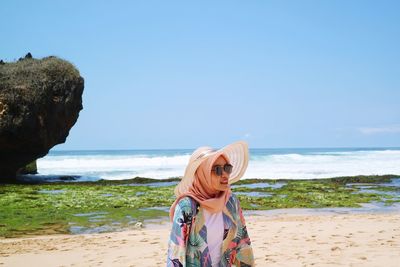 Woman standing at beach against sky