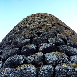 Low angle view of rocks on rock against clear blue sky