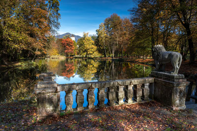 Statue by lake against sky during autumn