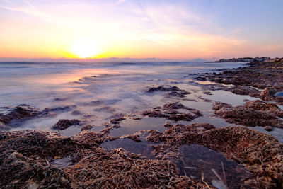 Scenic view of beach against sky during sunset