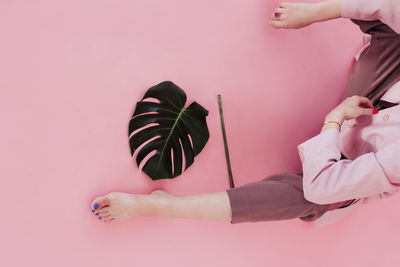 Low section of woman holding pink flowers against wall