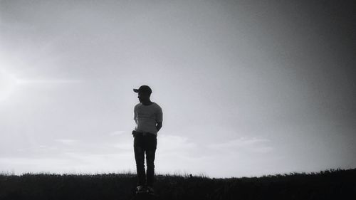 Rear view of silhouette man standing on field against sky