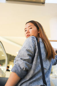 Low angle portrait of woman standing in shopping mall