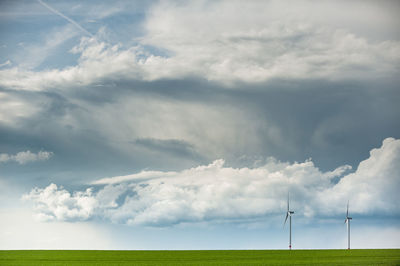 Windmill on field against cloudy sky