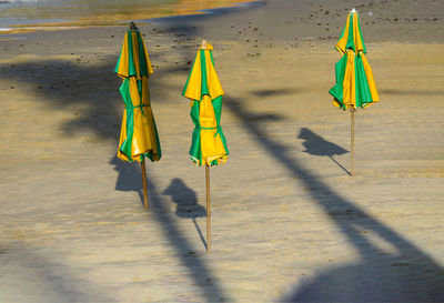 Closed yellow and green parasols at sandy beach